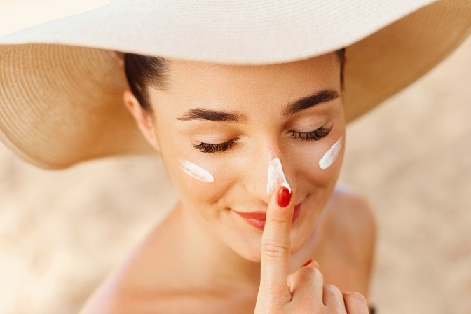 Eine Frau cremt sich mit Sonnenschutz gegen Hautalterung ein