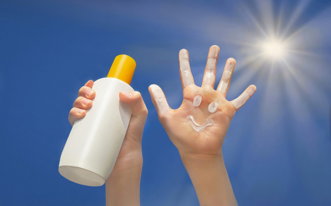 Handfläche mit Smiley aus Sonnencreme