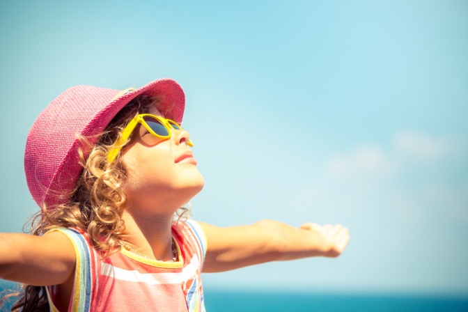 Ein Kind trägt Sonnenschutz (Sonnenbrille, Sonnenhut)