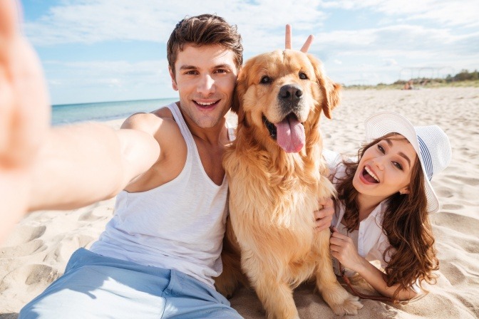 Ein Mann, eine Frau und ein Hund liegen am Strand zusammen