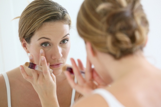 Eine Frau sieht ihre Augen im Spiegel an und benötigt Anti Aging Tipps
