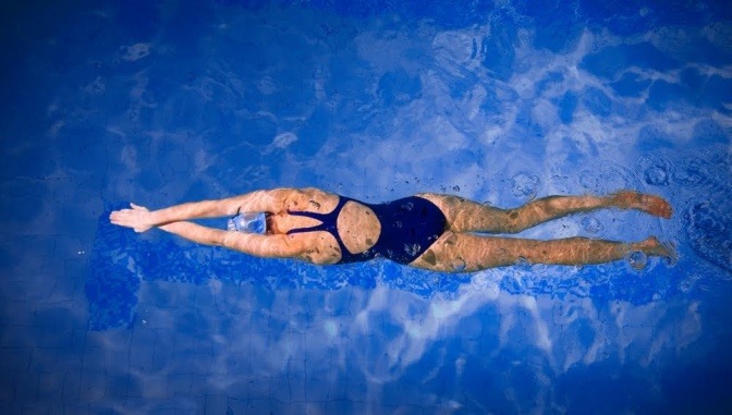 Eine Aufnahme aus der Vogelperspektive auf eine Frau, die in einem Swimmingpool schwimmt. 