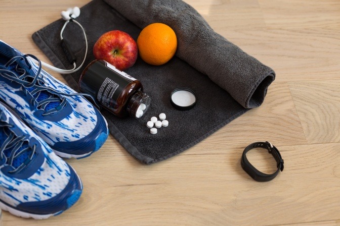Sportsachen liegen neben Obst und Tabletten