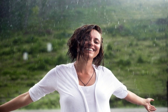 Frau mit starkem Immunsystem steht glücklich im Regen