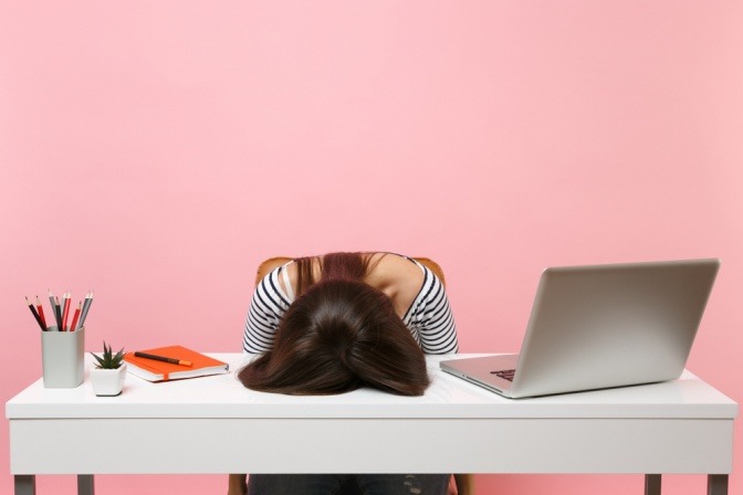 Frau am Schreibtisch überfordert fördert Akne durch Stress