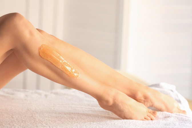 Eine Frau hat eine Sugaringpaste auf den Beinen 