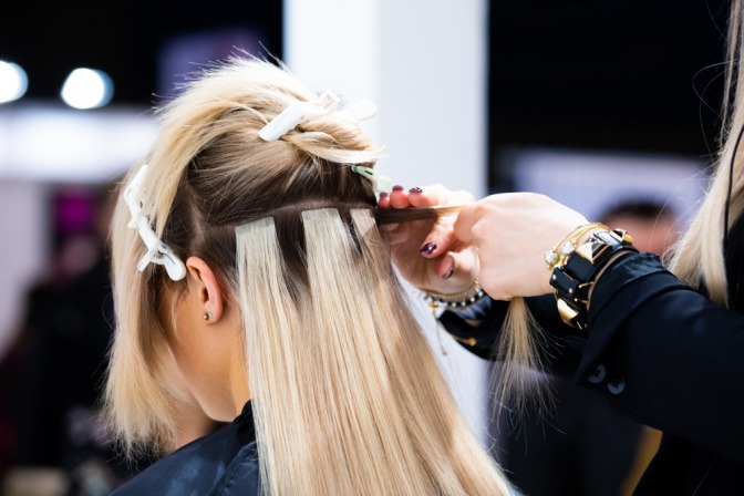 Frau bekommt beim Friseur Tape Extensions