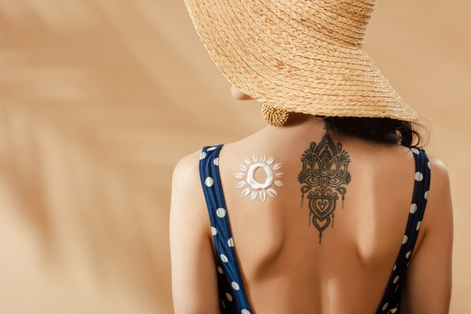 Sonnencreme auf tätowiertem Rücken einer Frau