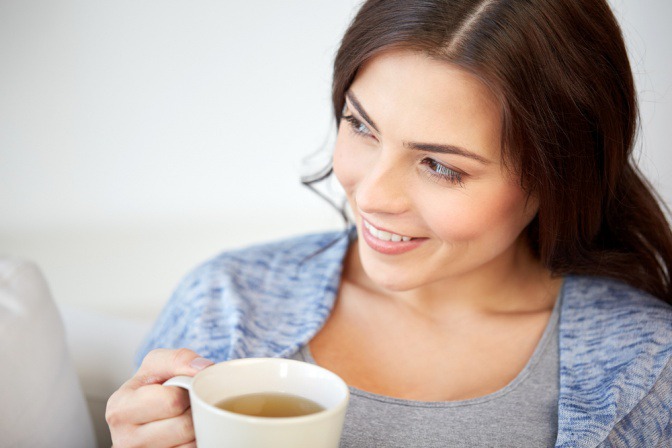 Eine Frau hält eine Tasse Tee in der Hand und fragt sich, ob Tee trinken gesund ist