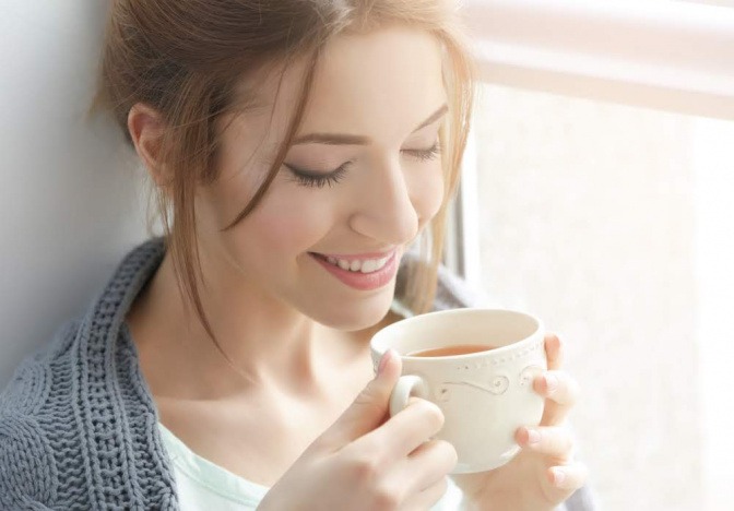 Frau trinkt aus einer Tasse.