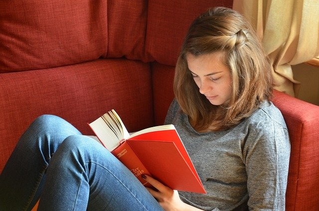 Junges Mädchen liest ein Buch auf der Couch