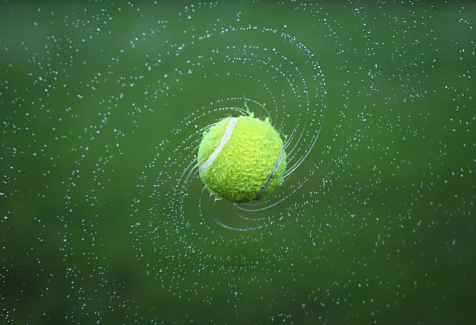 Ein Tennisball spritzt Wasser von sich