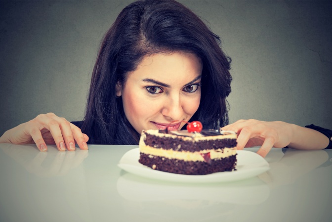 Frau versucht dem Hunger auf Kuchen zu widerstehen