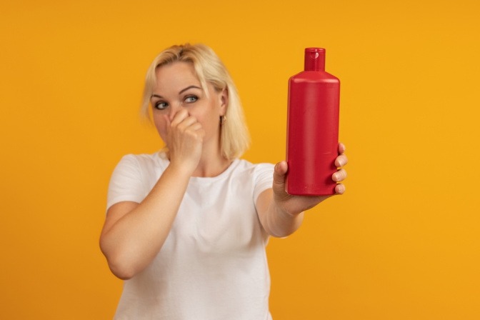 Eine Frau mit einer Trinkflasche hält sich die Nase zu