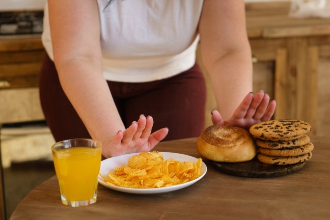 Frau schiebt ungesundes Essen weg.