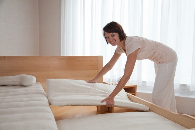 Frau nimmt Teil einer Untermatratze aus einem Bett