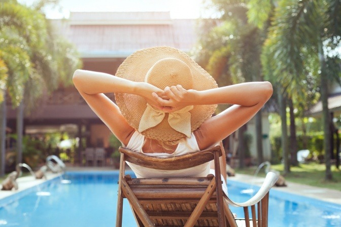 Eine Frau sitzt entspannt im Urlaub mit einem Beauty Bag