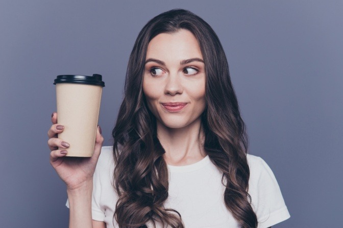 Frau mit Coffee-to-go Tasse in der Hand.