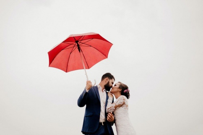 Ein Mann küsst eine Frau, in der Hand einen Regenschirm, um Sicherheit zu vermitteln