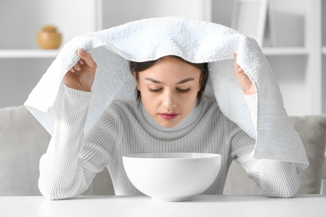Frau macht Dampfinhalation als Hausmittel bei einer verstopften Nase