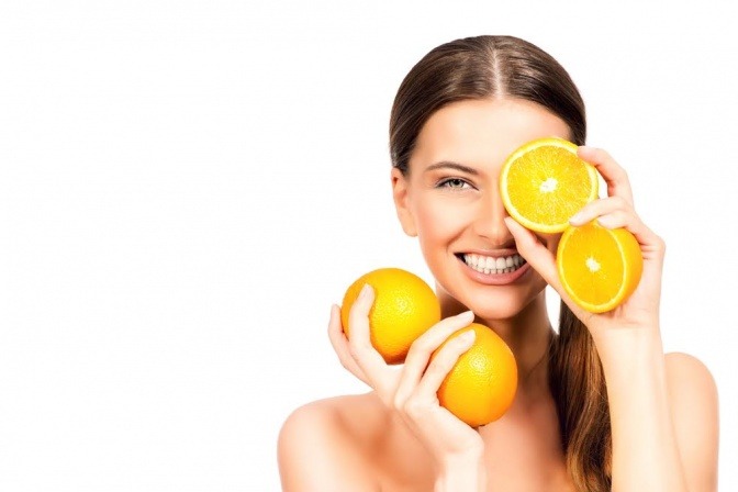 Frau mit Orangen vor dem Gesicht.