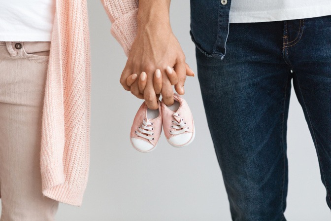 Paar hält gemeinsam ein Paar Babyschuhe