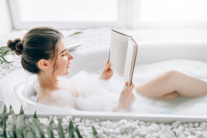 Frau mit Buch in der Badewanne.