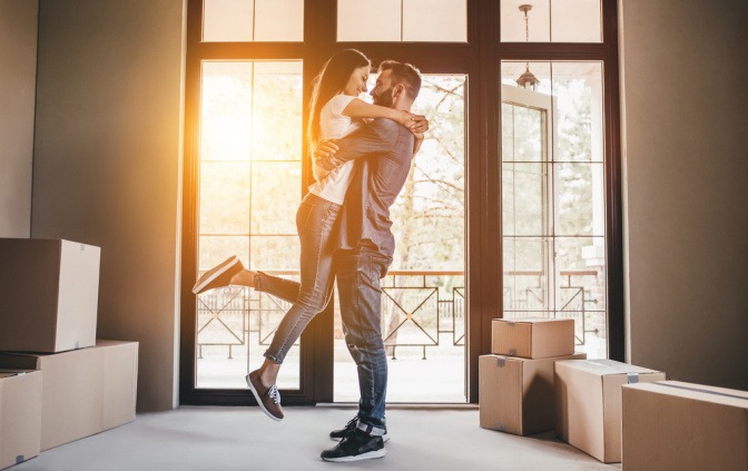 Wann zusammenziehen - glückliches Paar umarmt sich während des Kisten auspackens in der gemeinsamen neuen Wohnung. 