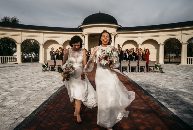 Zwei Frauen laufen nach der Hochzeit über einen großen Platz