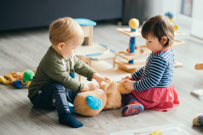 Zwei kleine Kinder sind ins Spiel vertieft.