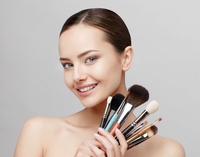 Frau zeigt verschiedene Make-up-Pinsel in die Kamera