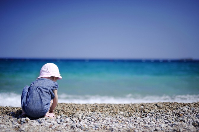 Kind am Strand spielt mit Steinen