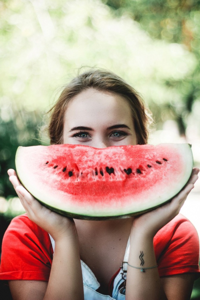 Eine Frau hält eine Wassermelone, die Lycopin enthält