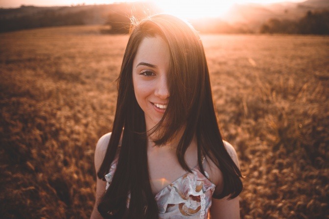Eine lächelnde junge Frau in einem Weizenfeld.