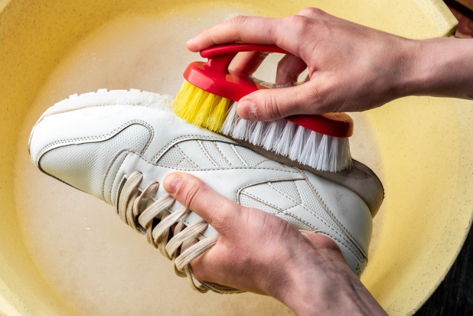 Grober Schmutz von weißen Sneakern wird mit Bürste entfernt