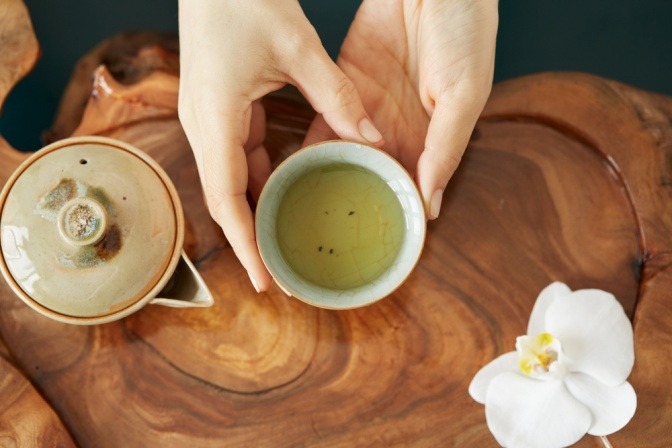 Eine Frau hält eine Tasse mit zubereitetem weißen Tee