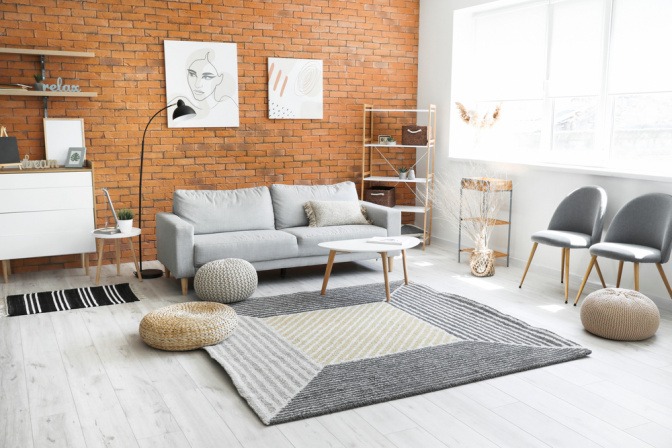 Ein in grau gehaltenes Wohnzimmer mit Teppich, Sofa und Stühlen