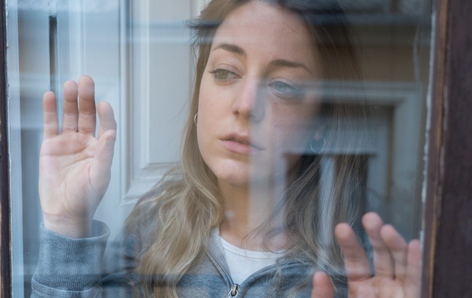 Eine Frau schaut traurig aus dem Fenster als würde sie sich wertlos fühlen