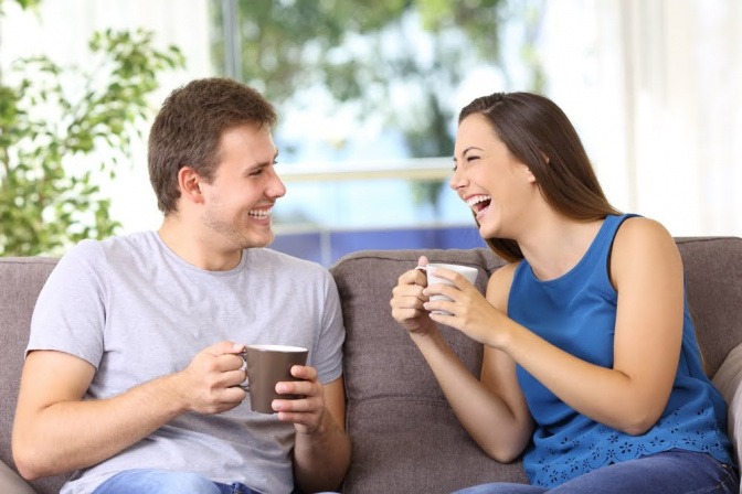 Ein Paar sitzt gemeinsam auf dem Sofa und führt eine entspannte, fröhliche Unterhaltung.