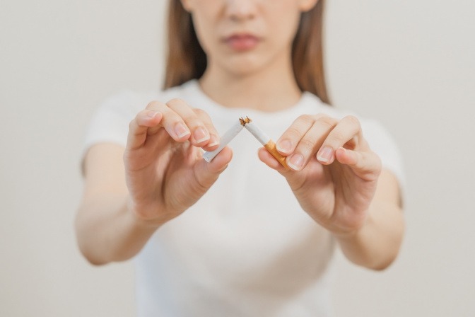 Eine Frau bricht eine Zigarette in zwei Teile