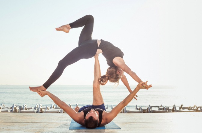 Junges Paar beim Acroyoga am Strand.