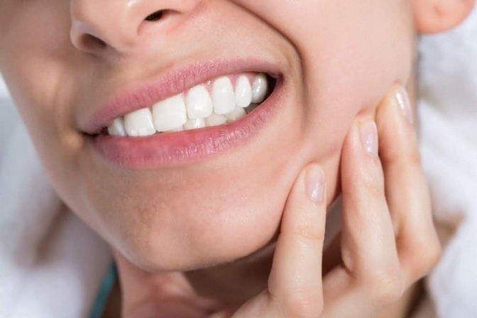 Eine Frau hat Schmerzen bei den Zähnen und muss ev. Zahnfleischtaschen reinigen
