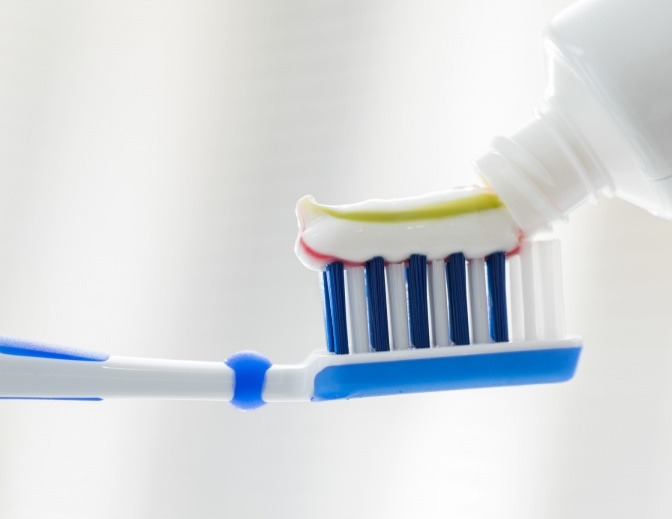 Auf eine Zahnbürste wird Zahnpaste aufgetragen