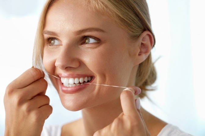 Frau benutzt Zahnseide gegen Mundgeruch