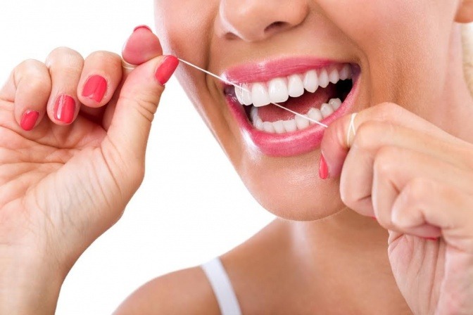 Eine Frau reinigt ihre Zähne mit Zahnseide 