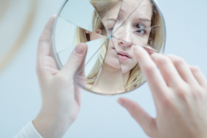 Das Spiegelbild einer Frau ist auf einem zerbrochenen Spiegel