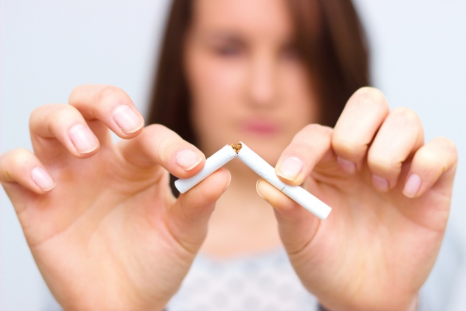 Frau bricht Zigarette in der Mitte durch