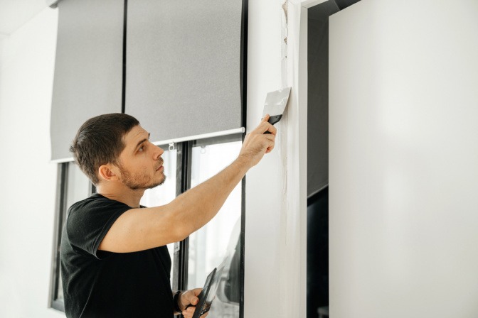 Mann repariert undichte Stelle in Schlafzimmerwand. 