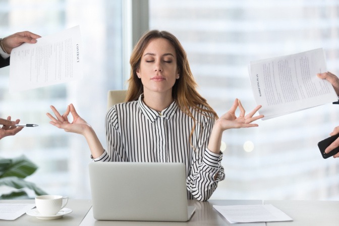 Frau in Meditationspose am Arbeitsplatz.