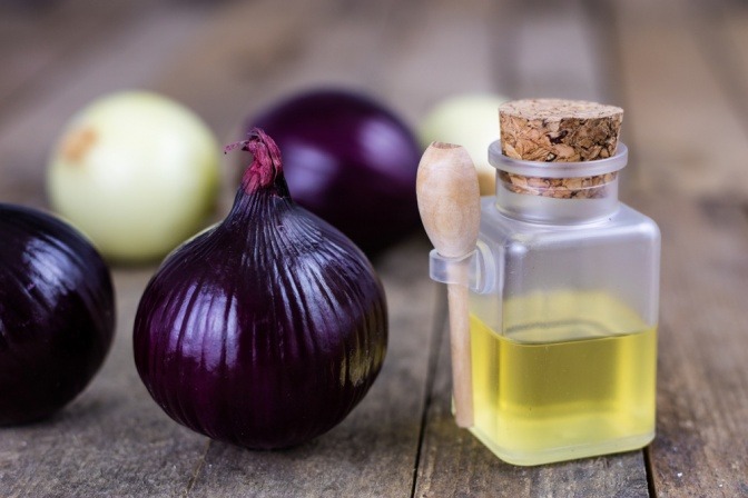 Zwiebeln liegen neben Zwiebelsaft für Husten